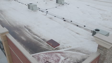 rooftop-damage-covered-in-white-tarp-at-building,-aerial-dynamic