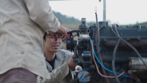 two people repairing a tractor engine