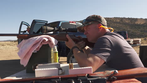 caucasian man fires r-25 30-06 rifle, target practice at range, slider shot