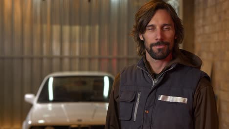 car mechanic man in vest holds out keys to car in background, slow motion