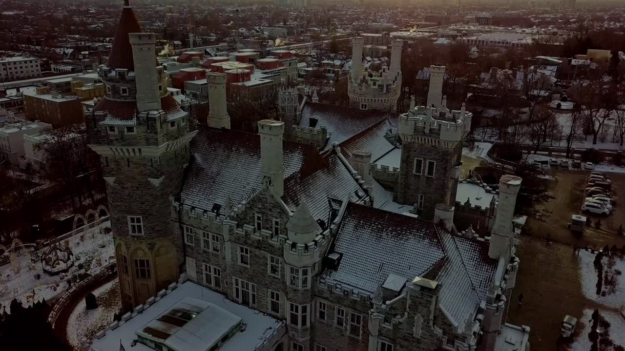 Fresh Snow on the Red Tile Roof of an Old Castle, Aerial Tilt Down. Scenic Drone View of the Historic Luxury Mansion Casa Loma in Downtown Toronto Canada at Winter Sunset