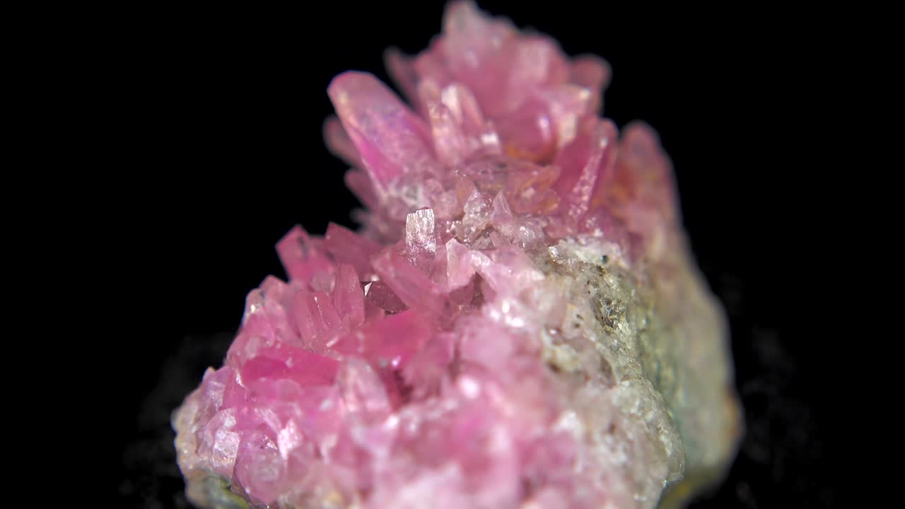 la rotación sin problemas de un mineral rosado (cuarzo rosa) frente a un fondo negro