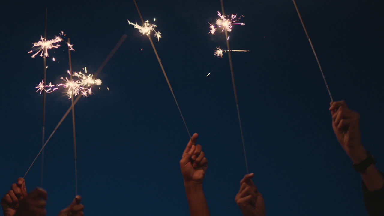 hands holding sparklers celebrating new years eve holiday at night