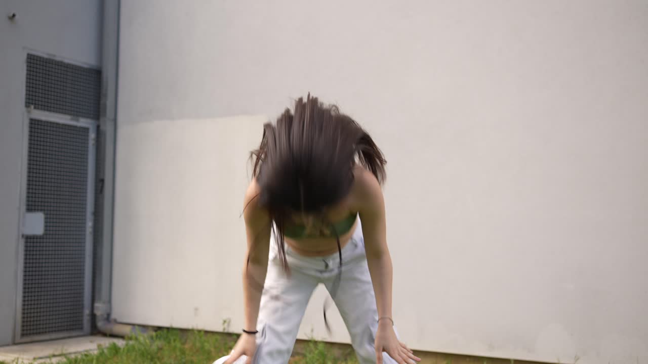Woman dancing in front of a concrete wall