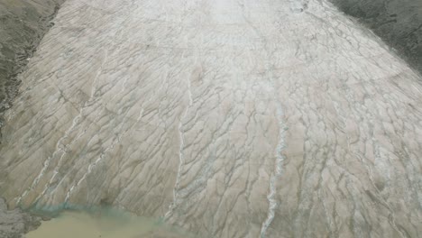 Aerial-dolly-in-lowering-on-Columbia-Icefield-Glacier-betweem-mountains-at-Banff-National-Park,-Alberta,-Canada