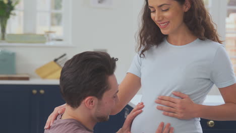 Excited-Pregnant-Transgender-Couple-At-Home-In-Kitchen-With-Man-Listening-To-Baby's-Heartbeat