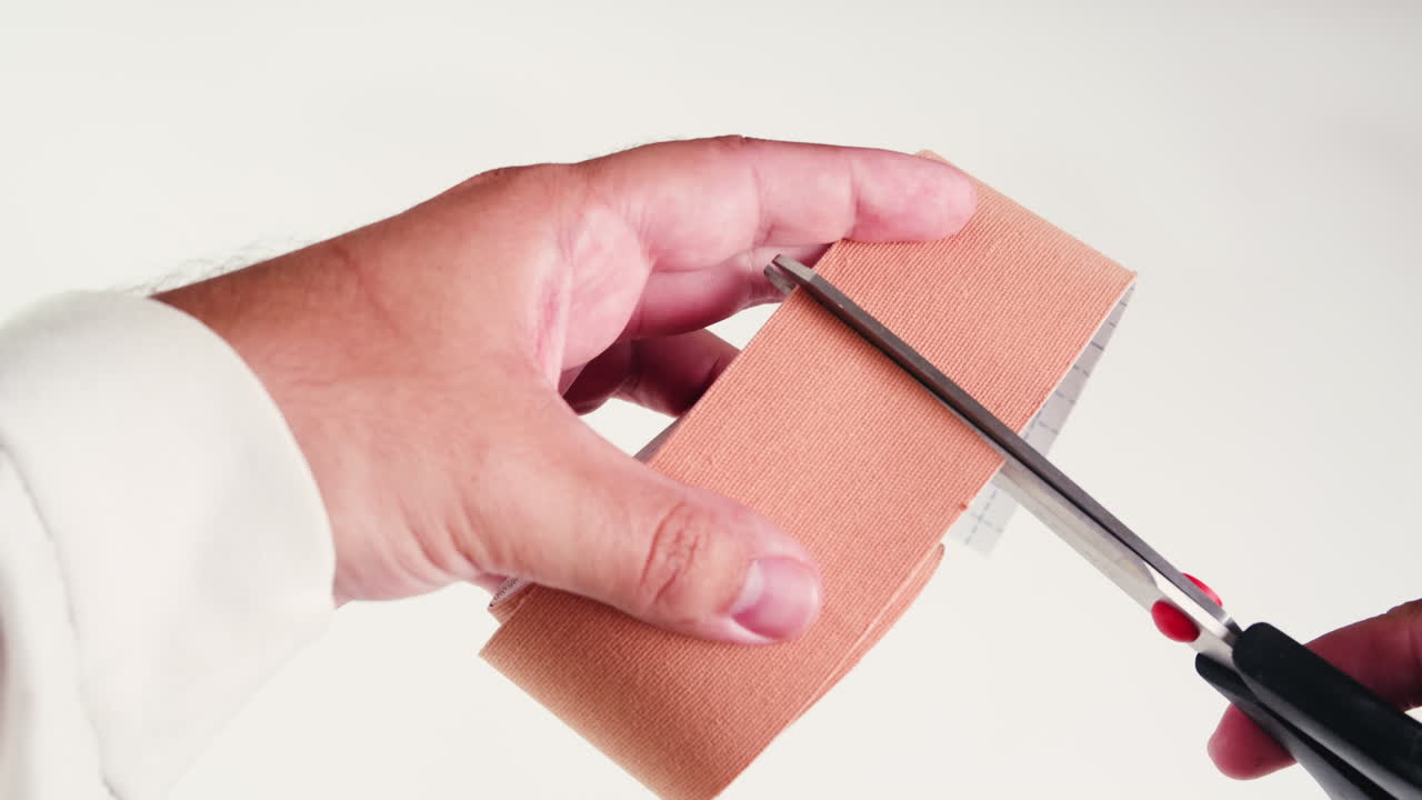 Kinesiology medical taping, doctor Physical therapist applying elastic surgical tape to patient body, treating injured knee young athlete.Post traumatic rehabilitation, sport physical therapy recovery