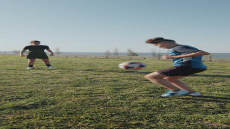 two athletic girls passing soccer ball on sunny day