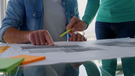 front view of caucasian business people discussing over blueprint in the office 4k