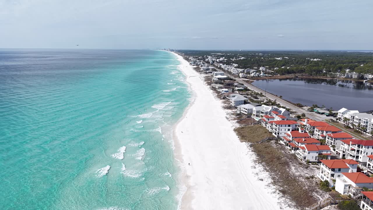 Volo in avanti con drone lungo la costa di sabbia bianca di Santa Rosa Beach con ville fronte mare, 30A, Florida, USA.