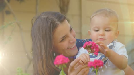 Animation-of-glowing-spots-over-happy-caucasian-mother-with-daughter-holding-flowers