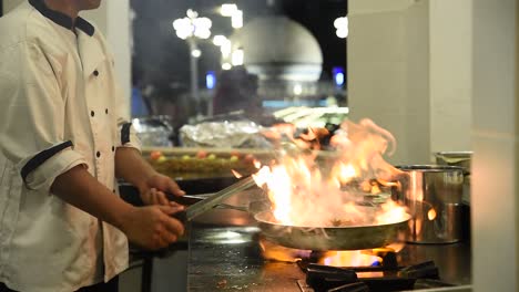 Chef-preparing-food-in-a-saucepan-on-the-gas-stove-of-a-restaurant-kitchen