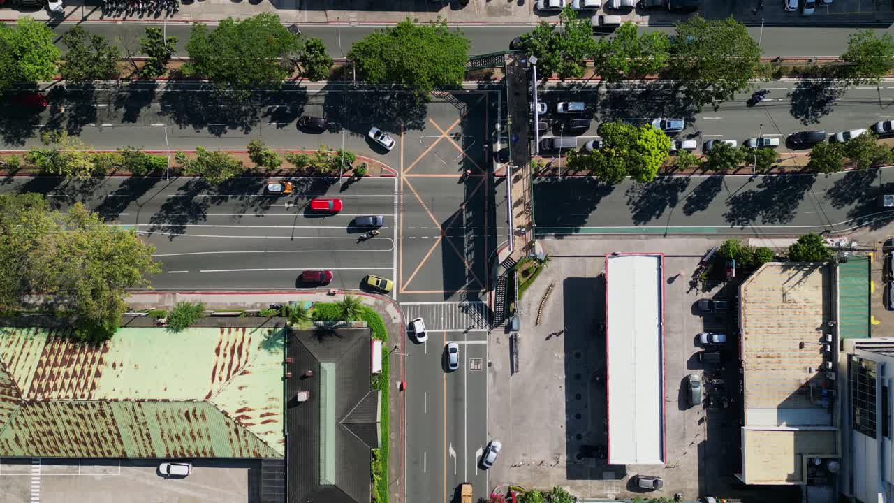 Aerial top-down pullback of cars and motorcycles driving along three-way intersection at Ortigas Avenue Highway - Metro Manila, Philippines