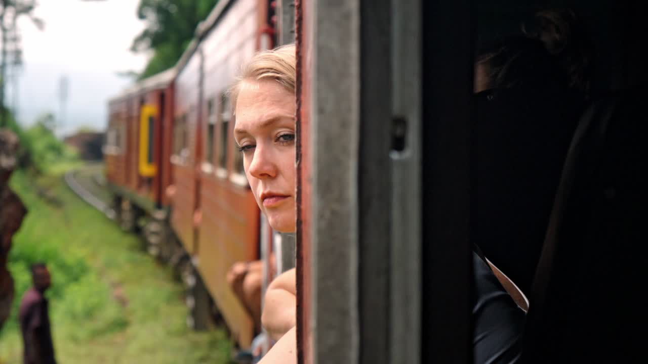 A captivating moment inside the Ella-Kandy train in Sri Lanka, where a woman gazes out of the window, taking in the lush, green landscape.