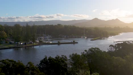 aerial view of brunswick heads river at sunset with lush greenery and distant mountains under soft, golden lighting