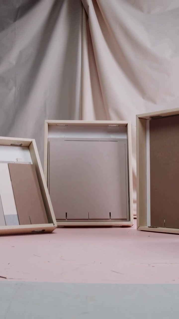 Vertical video: Starting camera framing central wood frame on pink base, emphasizing staples