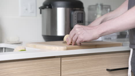 male cutting plantain on a bamboo cutting board, with pressure cooker in background (mcu)