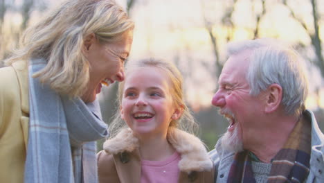 portrait of grandparents with granddaughter outside walking through winter countryside