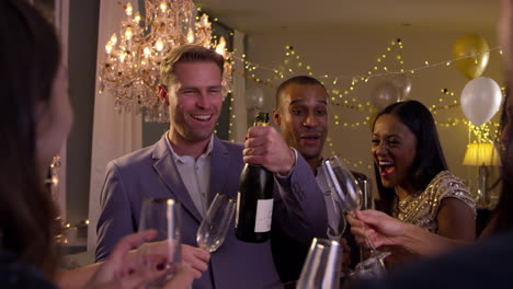 friends open champagne as they celebrate at party together