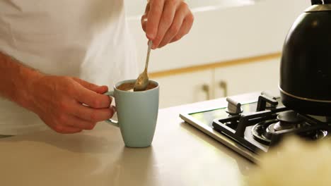 Man-stirring-coffee-in-kitchen-at-home-4k