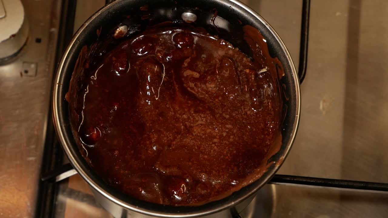 chocolate con leche caliente derretido con avellanas y burbujas en la estufa de gas en una olla pequeña