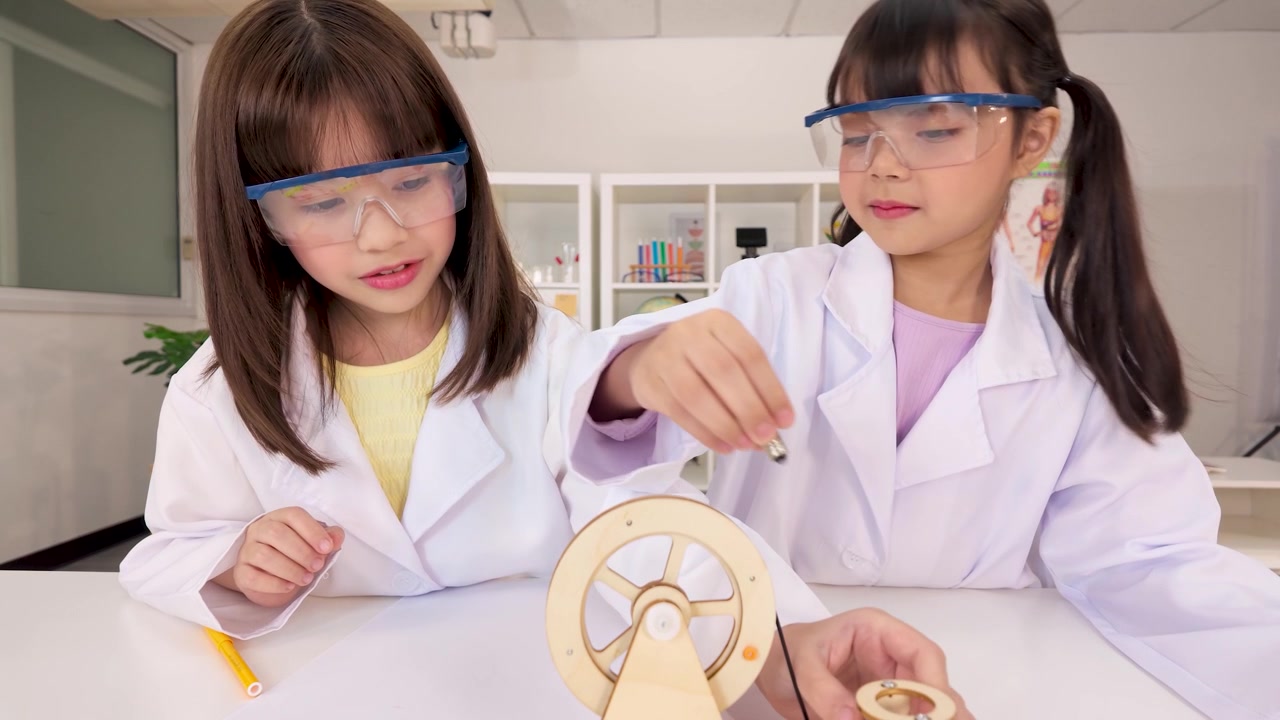 Kaksi nuorta tyttöä suojalasit ja laboratoriotakit päällään suorittaa STEM-kokeen luokkahuoneessa.