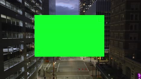 Drone-shot-of-a-Green-Screen-filling-the-frame-inside-a-illuminated-city---Chroma-Key