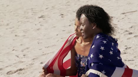 pareja envuelta en bandera estadounidense sentada juntos en la playa 4k