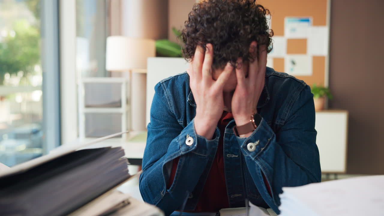 Giovane uomo stressato sopraffatto dalle scartoffie in ufficio