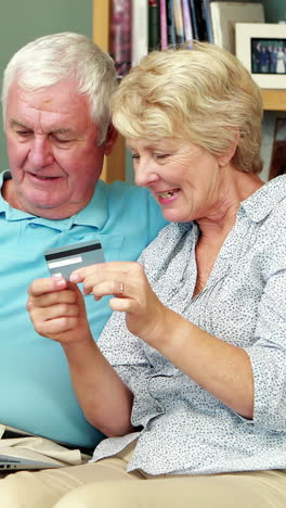 pareja de ancianos usando una computadora portátil y una tarjeta de crédito