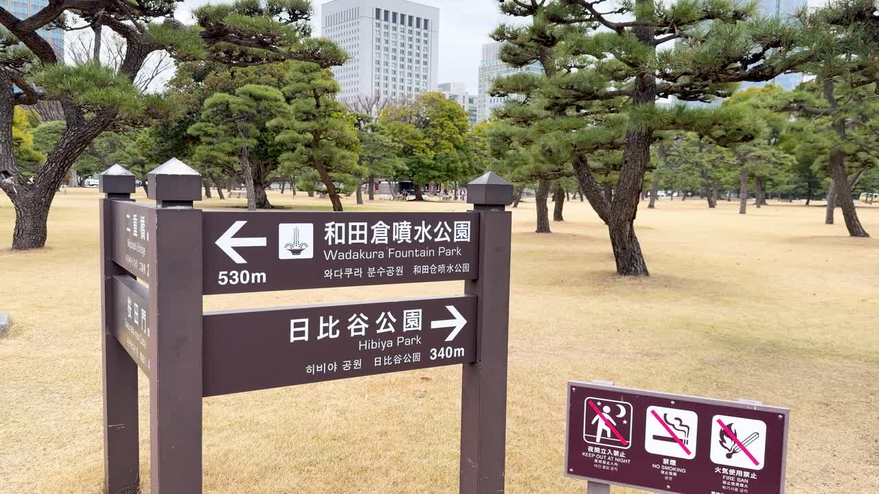 A slow panning shot reveals directional signs pointing toward Wadakura Fountain Park and Hibiya Park