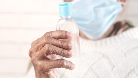 elderly person holding hand sanitizer bottle while wearing mask