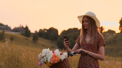 Ziemlich-Süßes-Mädchen,-Das-An-Einem-Sonnigen-Tag-Im-Park-Mit-Palmen-Neben-Ihrem-Fahrrad-Ein-Smartphone-Benutzt.-Hübsches-Mädchen,-Das-An-Einem-Sonnigen-Tag-Im-Park-Neben-Ihrem-Fahrrad-Ein-Smartphone-Benutzt.