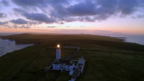 smooth aerial approach to loop head lighthouse beaming under a stunning, vibrant sky at sunrise