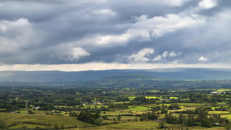 time lapse of rural farming landscape with grass fields and hills during a passing storm rainy day in ireland