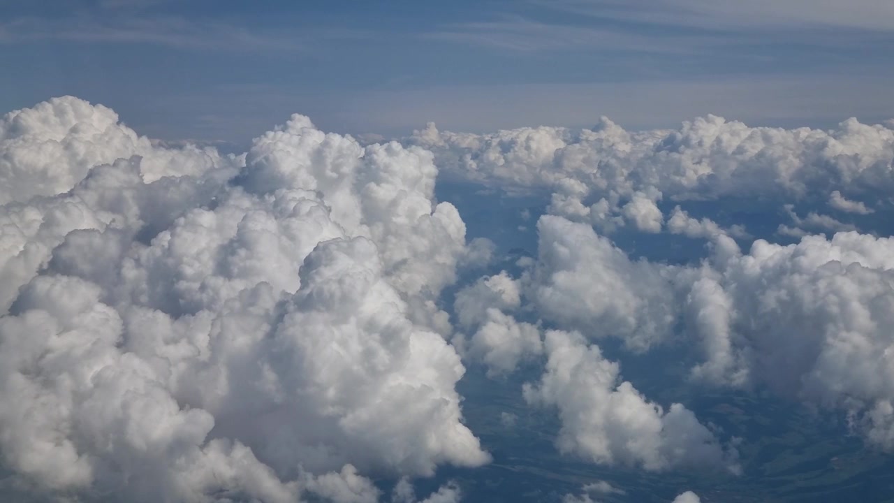 Peaceful aerial view from an airplane window above a sea of fluffy white clouds, with a clear blue sky and distant horizon creating a relaxing, meditative atmosphere during air travel