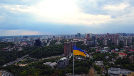 ukrainian flag on a tall pillar against kyiv city background