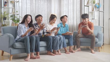 teenagers playing mobile games on a couch