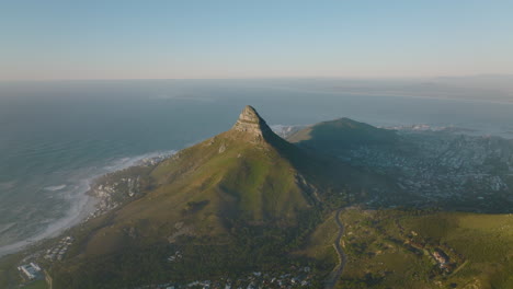 Tiro-Elevado-De-Pico-Puntiagudo-Con-Fuertes-Pendientes-Que-Caen-Al-Suburbio-Por-Un-Lado-Y-A-La-Costa-Del-Mar-Por-El-Otro.-Ciudad-Del-Cabo,-Sudáfrica