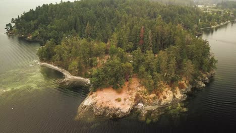 Aerial-Daytime-Wide-Shot-Flying-Over-Green-Ocean-Orbiting-A-Rocky-Tree-Covered-Point-And-Sand-Beach-Showing-Underwater-Rocks-And-Kelp-In-Gulf-Islands-British-Columbia-Canada