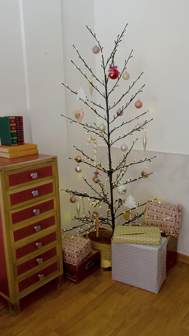 Decorazioni minimal per l'albero di Natale con regali accanto a un mobile in legno