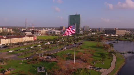 american flag and veterans memorial park in lake charles with the damaged capital one building in louisiana post hurricane laura