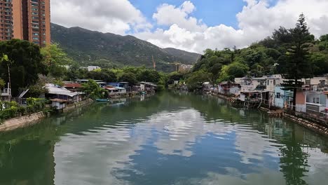 pan left view across calm waterway surrounded by village buildings in hong kong