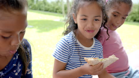 in school, three young biracial female students enjoying lunch outdoors