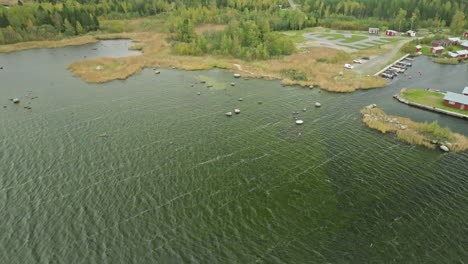 autumn trees at the lakeshore with mooring boats and village in finland