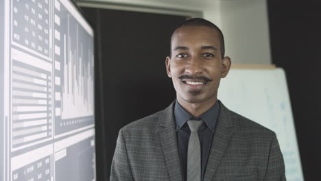 friendly black finance professional posing near big screen