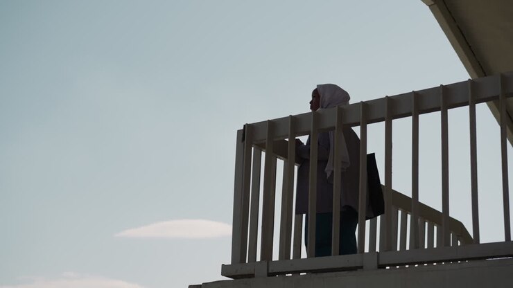 Muslim lady stands on ground under bridge against clear sky