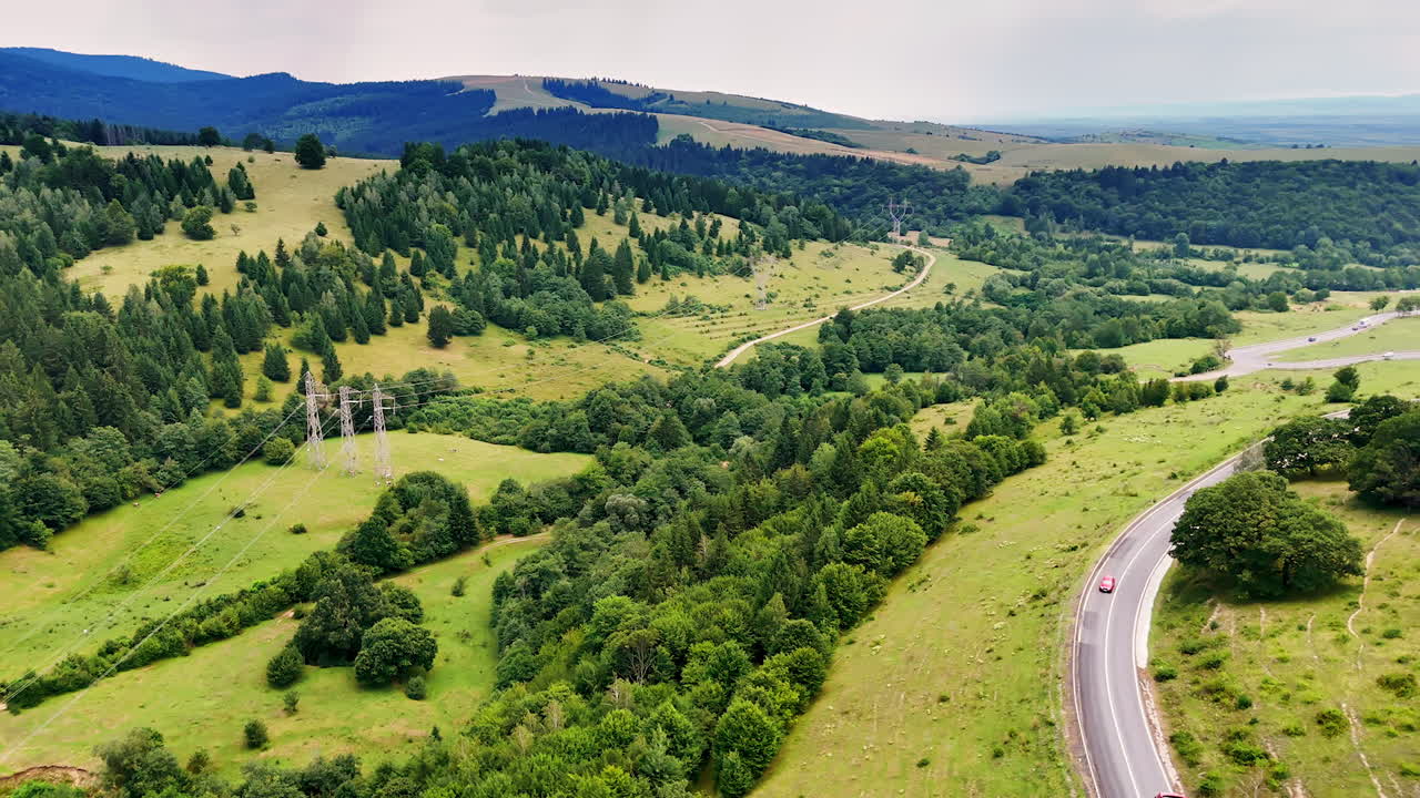 Green hills with winding road. Lush green hills stretch under a cloudy sky, with a winding road leading through the vibrant landscape