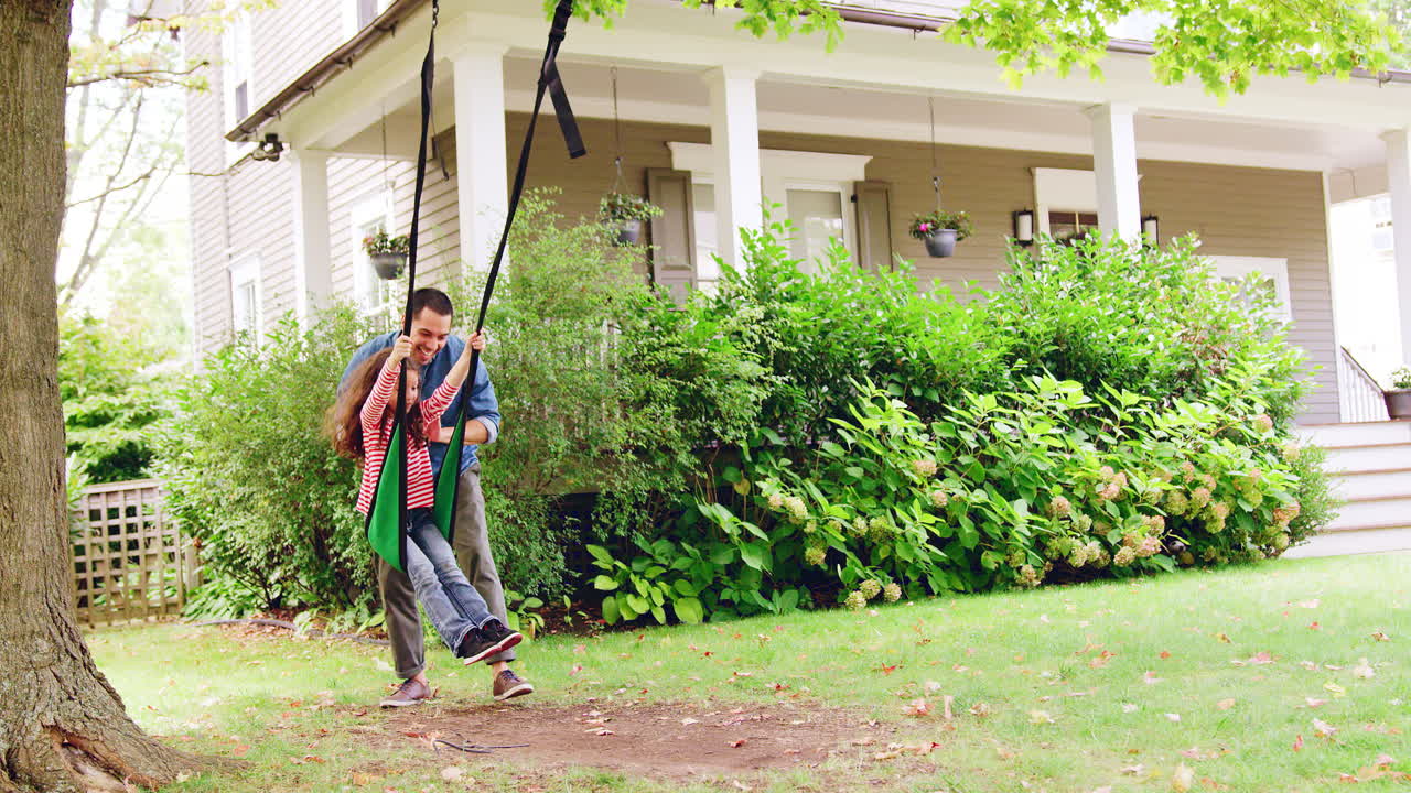 padre empujando a su hija en el columpio del jardín en casa en cámara lenta