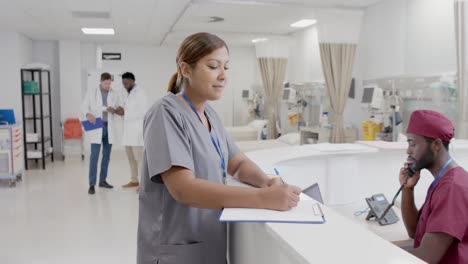 portrait of happy diverse male and female nurses talking at reception in slow motion, unaltered